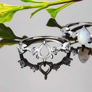 May include: A silver ring with a pear-shaped setting and small round stones on each side. The ring is engraved with "JEWELETS 925".