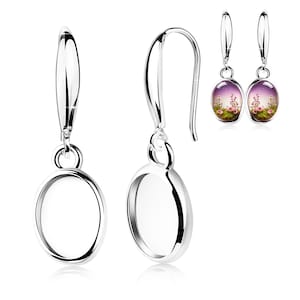 May include: Silver-toned dangle earrings. One pair features an oval frame, while the other has an oval design with a floral scene. The earrings have a hook closure and a polished finish, reflecting light.