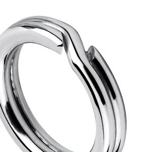 Peut inclure: Un porte-clés en métal argenté avec une surface lisse et arrondie. L'anneau est conçu pour être durable et sécurisé pour attacher des clés ou d'autres petits objets.