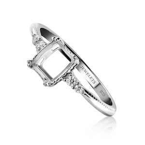 May include: Silver ring with a square-shaped setting for a gemstone. The ring has a delicate design with small diamonds on the band. The ring is marked "JEWELETS 925".
