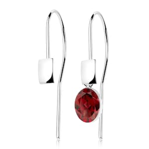 May include: A pair of silver drop earrings. Each earring has a polished silver hook with a rectangular detail and a dangling, round, faceted, deep red gemstone. The gemstones are set in a silver bezel.