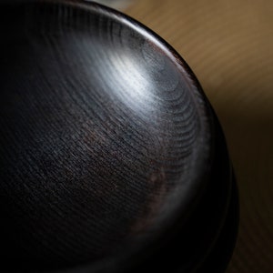 Pu&ograve; includere: Una ciotola di legno marrone scuro con una finitura liscia e lucida. La ciotola &egrave; vuota e sembra essere fatta di un unico pezzo di legno.