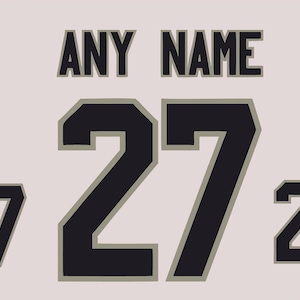 Peut inclure: Un ensemble de chiffres et de texte de style athlétique noir présentant l'expression ANY NAME dans une police grasse sans empattement. Le design comprend un grand nombre 27 au centre, flanqué de deux versions plus petites du nombre 27, avec un contour gris.