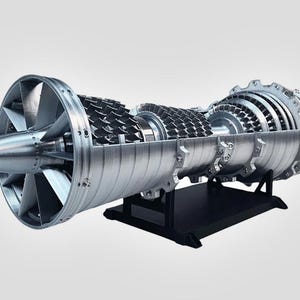 Puede incluir: Modelo detallado en sección transversal de un motor a reacción, que muestra los componentes internos. El motor plateado presenta aspas de ventilador, álabes de turbina y varias piezas mecánicas. Está montado sobre un soporte negro.