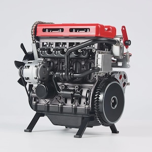 May include: A detailed model engine with a red top, black components, and silver accents. The engine features a fan, gears, and various mechanical parts, mounted on a black stand. The model is designed to showcase the internal workings of an engine.