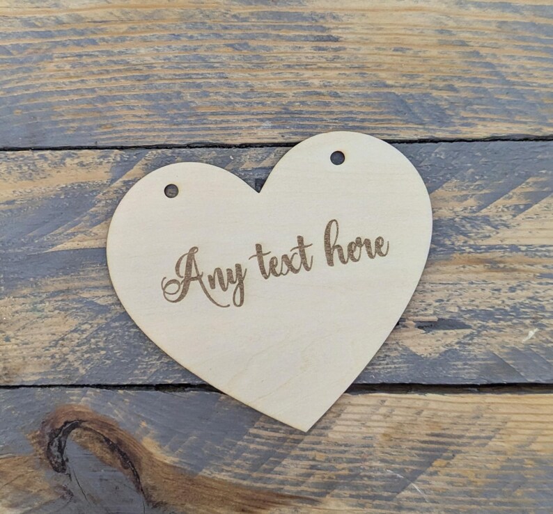 May include: A wooden heart-shaped sign with holes for hanging. The sign is blank and has the text "Any text here" engraved on it.
