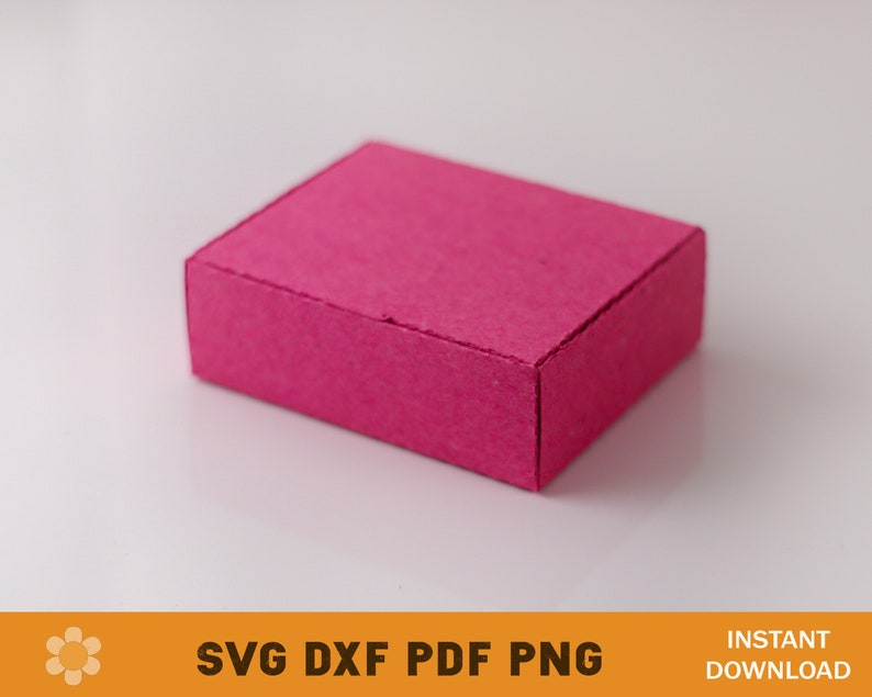 Puede incluir: Una peque&ntilde;a caja rectangular de color rosa hecha de cart&oacute;n. La caja tiene una superficie texturizada y est&aacute; sobre un fondo blanco.