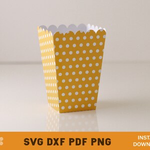 Puede incluir: Una caja de palomitas de ma&iacute;z de papel amarilla y blanca con lunares y un borde superior festoneado.