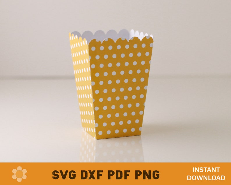 Puede incluir: Una caja de palomitas de ma&iacute;z de papel amarilla y blanca con lunares y un borde superior festoneado.