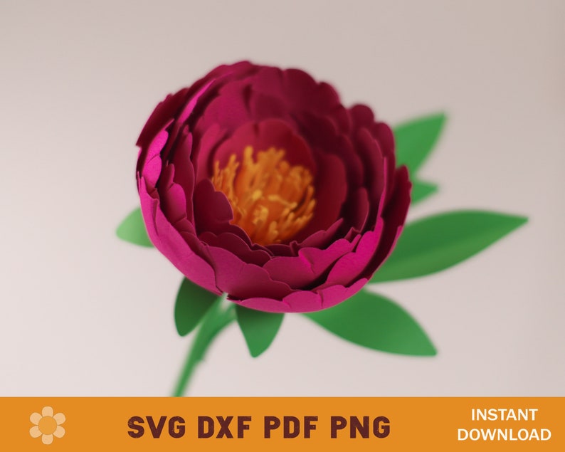 May include: A paper flower with a deep pink center and yellow stamen. The flower is surrounded by green leaves and has a long stem.