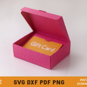 Puede incluir: Una caja de regalo rosa con una tarjeta de regalo amarilla en el interior que dice "Gift Card".