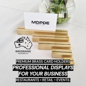 Puede incluir: Un conjunto de tarjeteros de latón de varios tamaños, con una tarjeta de visita que muestra el texto "MDPDE BRISBANE AUSTRALIA". La imagen también incluye el texto "PREMIUM BRASS CARD HOLDERS PROFESSIONAL DISPLAYS FOR YOUR BUSINESS RESTAURANTS • RETAIL • EVENTS".