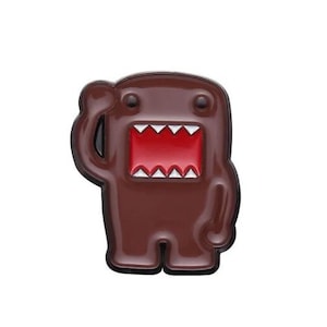 Puede incluir: Una figura marrón de Domo-kun con boca roja y dientes blancos, saludando con un brazo levantado. La figura tiene un acabado brillante y está sobre un fondo blanco. El diseño es un personaje de dibujos animados.