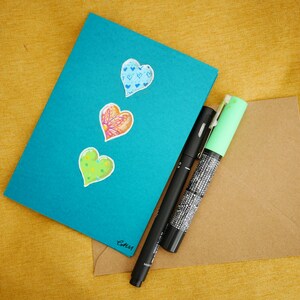 Una tarjeta dibujada a mano con tres corazones brillantes. Única y hermosa para el día de San Valentín. Dibujo original, no una impresión.