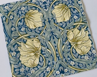 May include: Square fabric with a floral pattern featuring large cream-colored flowers, green leaves, and small white blossoms against a dark blue background. The design has a vintage, botanical aesthetic.