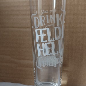 May include: A clear glass beer stein with the text "You can drink good Feldi Hell with good friends" etched on the side.