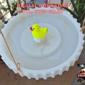 May include: A white, circular, 3D-printed bird bath with a yellow rubber duck toy. The bird bath has a gear-like edge and is suspended by twine. The text "DIGITAL DOWNLOAD STL, STEP FILES" is at the top.