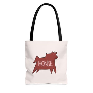 May include: A white tote bag with black handles and a red silhouette of a dog with the word "HONSE" written in pink inside the silhouette.