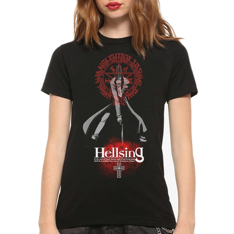 May include: A black short-sleeve t-shirt featuring a graphic of a character in a long coat holding a sword. Above the character is a red circular seal with text. Below is the word Hellsing, a cross, and the text: In the name of God, impure souls of the living dead shall be banished into eternal damnation. Amen.