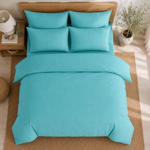 Turquoise cotton duvet cover set styled in a bright coastal bedroom with matching pillow covers, wooden furniture, beach wall art, and natural sunlight.