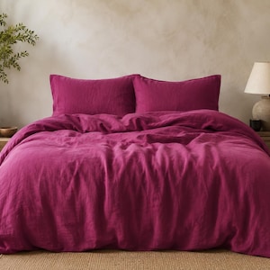 May include: A vibrant magenta bedding set consisting of a duvet cover and two matching rectangular pillowcases. The fabric has a visible, slightly textured weave, and the bedding is arranged neatly on a bed with a soft, draped appearance.
