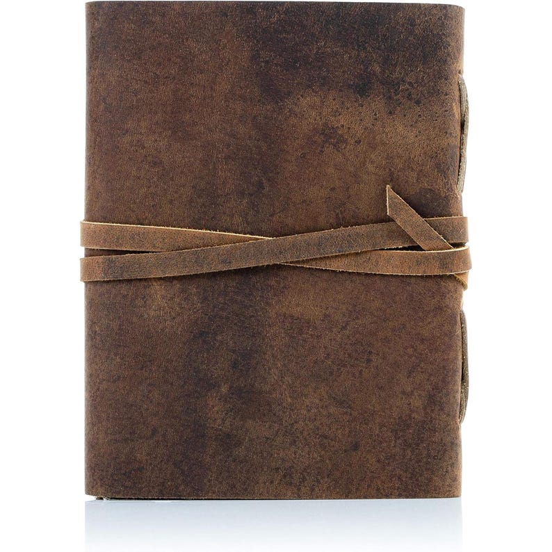 Puede incluir: Un diario de cuero marr&oacute;n con un aspecto desgastado. Tiene un cierre de correa de cuero y est&aacute; atado con un cord&oacute;n de cuero marr&oacute;n.