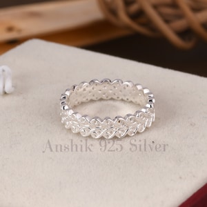 May include: A silver ring with a delicate, intricate design. The ring is made of 925 silver and is a simple, elegant piece of jewelry.