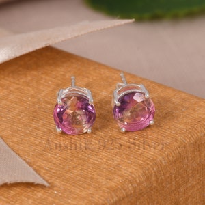 May include: A pair of silver stud earrings with round, pink and yellow ombre gemstones.