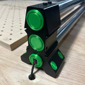Op de afbeelding: Een zwarte metalen basis met drie groene rubberen voetjes en een zwarte draad die uit de onderkant komt. De basis heeft drie groene rubberen cirkels aan de zijkant.