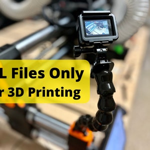 May include: A black GoPro camera mounted on a flexible tripod arm. The camera is pointed towards a 3D printer. The text "STL Files Only for 3D Printing" is displayed in yellow on a black background.