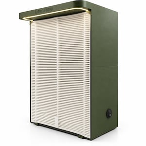 Pode incluir: Uma unidade de filtragem de ar Urban Fungi verde-oliva com um painel de filtro branco de pregas verticais na frente. O dispositivo possui uma faixa de luz integrada sob a borda superior e um interruptor preto circular no painel lateral.