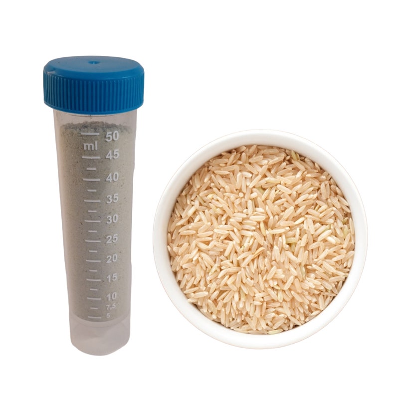 Pode incluir: Uma tigela branca cheia de arroz integral. Um cilindro graduado transparente com uma tampa azul est&aacute; cheio de um p&oacute; cinzento. O cilindro tem marcas em mililitros de 5 a 50.