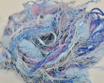May include: A pile of blue, white, and purple yarn with a sparkly silver thread. The yarn is fluffy and soft, and it would be perfect for knitting or crocheting.