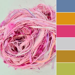 May include: A ball of textured art yarn featuring a mix of pink, magenta, and white fibers. The yarn consists of various strands including fuzzy, ribbon-like, and metallic threads intertwined to create a complex, multi-dimensional appearance.
