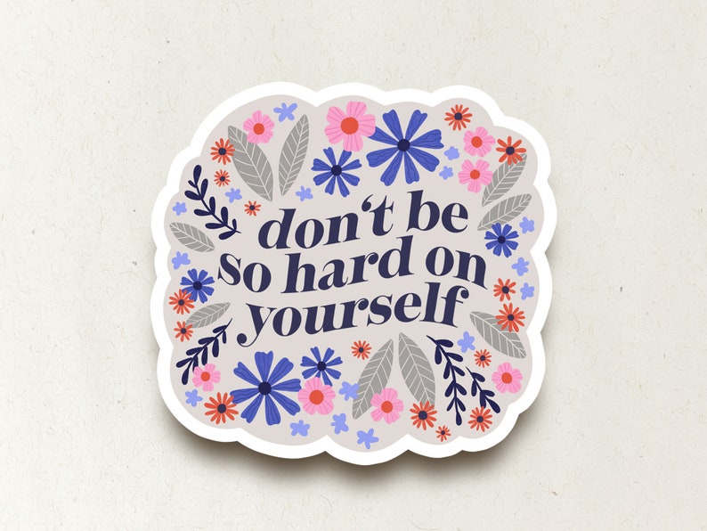 Puede incluir: Una pegatina con un dise&ntilde;o floral y el texto "no seas tan duro contigo mismo". Las flores son rosas, azules y rojas.