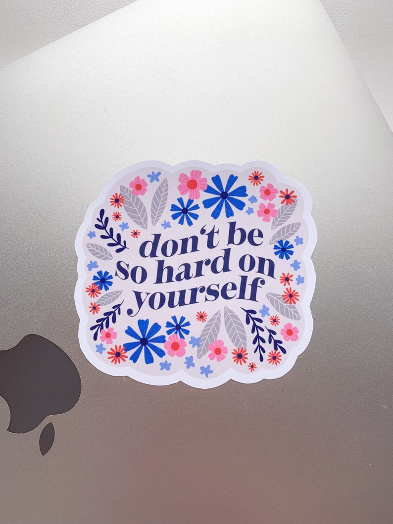 Puede incluir: Una pegatina blanca con un borde floral y el texto "no seas tan duro contigo mismo".