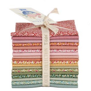 Könnte beinhalten: Ein Stapel gefalteter Stoffquadrate in verschiedenen Farben und Blumenmustern, zusammengebunden mit einem cremefarbenen Band mit der Aufschrift Tilda Quilt Collection. Das Stoffbündel enthält Töne in Rot, Rosa, Orange, Gelb, Grün und Blau.