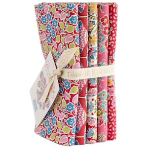 Könnte beinhalten: Ein Set mit sechs Stoff-Fat Quarters in einem roten, rosa und blauen Blumenmuster. Der Stoff ist mit einem weißen Band und einem Etikett mit der Aufschrift "Tilda" verpackt.