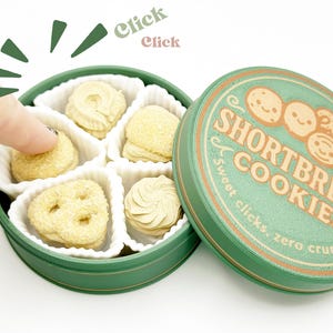 May include: A green tin of shortbread cookies with a lid that reads "Shortbread Cookies". The tin is open, revealing several shortbread cookies in various shapes. A finger is reaching for a cookie.