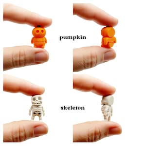 Peut inclure: Figurine miniature de citrouille orange et figurine miniature de squelette blanc. La citrouille est ronde avec une petite tige noire, et le squelette pr&eacute;sente un cr&acirc;ne et une cage thoracique d&eacute;taill&eacute;s. Le texte pumpkin et skeleton appara&icirc;t.
