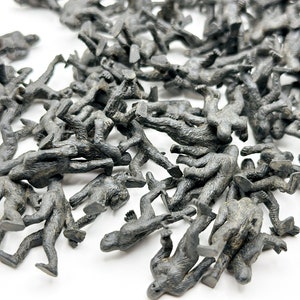 May include: A large group of small, gray plastic toy figures of Bigfoot or Sasquatch. The figures are scattered on a white surface.