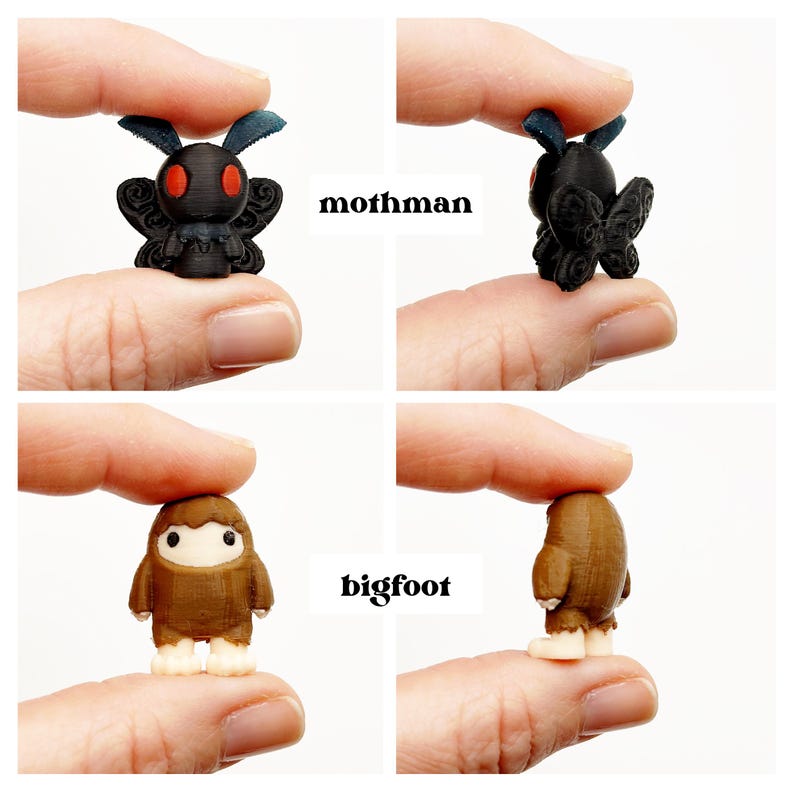 May include: A set of miniature figurines, including a black Mothman with red eyes and a brown Bigfoot. The figurines are held between fingers, with the text "mothman" and "bigfoot" displayed. These small figures are likely collectibles or toys.