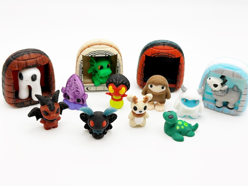 May include: A collection of colorful miniature figurines, including creatures and dwellings. The figurines feature various designs, such as a white ghost, a green dragon, and a brown creature. The collection is set against a white background.