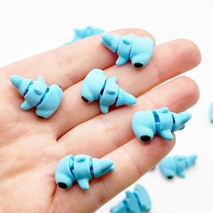 May include: A collection of light blue hammerhead shark charms. The charms are made of polymer clay and have black eyes. The charms are about 1 inch in size.