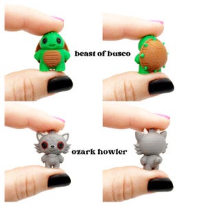 May include: Four small figurines: a green turtle with a brown shell, and a gray wolf-like creature. The turtle is labeled "beast of busco" and the wolf is labeled "ozark howler". The figurines are held up by fingers.