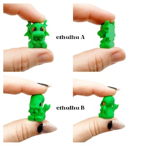 May include: Four small, green Cthulhu figurines are displayed. Two are labeled "cthulhu A" and two are labeled "cthulhu B". The figurines are held between fingers, showcasing their details. The figurines have orange eyes.