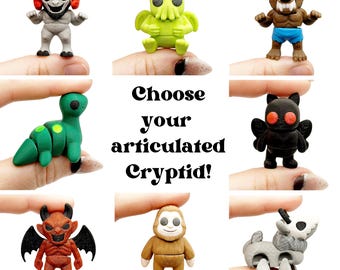 May include: A collection of articulated cryptid figurines in various colors. The figurines include a green Cthulhu-like creature, a werewolf, a mothman, a devil, a bigfoot, and a goat-like creature. The text "Choose your articulated Cryptid!" is also present.