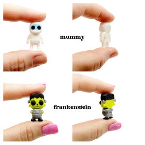 Peut inclure: Deux figurines miniatures, une momie blanche aux yeux bleus et un monstre de Frankenstein vert avec des cheveux noirs et des boulons argent&eacute;s, pr&eacute;sent&eacute;es de face et de dos avec les &eacute;tiquettes textuelles mummy et frankenstein.