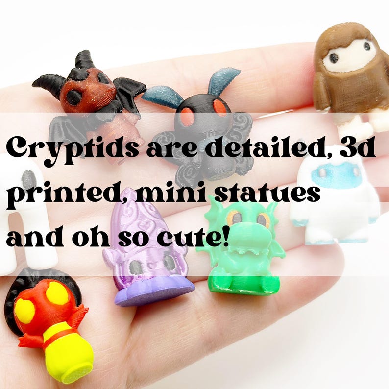 May include: A collection of colorful, 3D-printed mini cryptid statues. The text in the image reads "Cryptids are detailed, 3d printed, mini statues and oh so cute!" The statues include a red and yellow creature, a purple creature, and a green dragon.