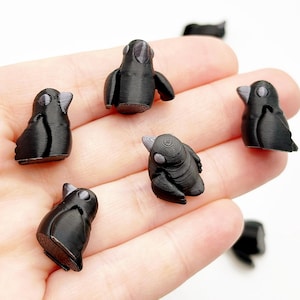 Könnte beinhalten: Ein Set mit sechs kleinen schwarzen Vogelfiguren mit grauen Akzenten. Die Figuren sind aus Kunststoff und etwa 2,5 cm hoch.